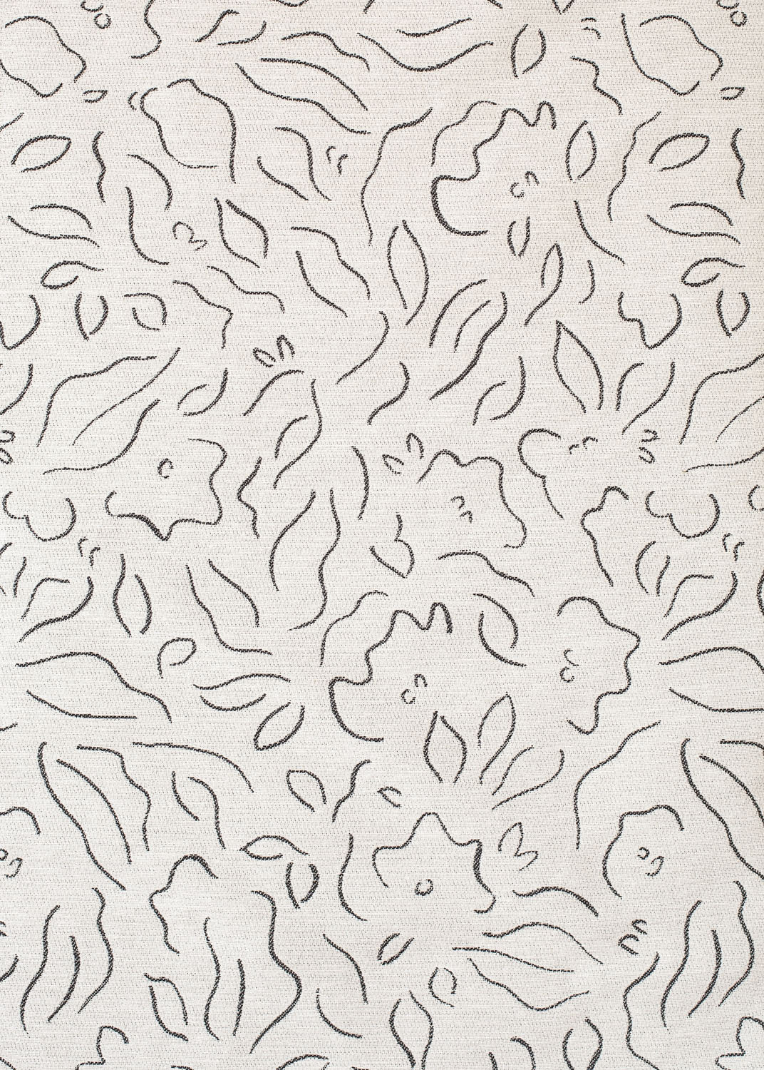Detail of fabric in a minimalist floral print in charcoal on a cream field.