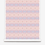 Partially unrolled wallpaper yardage in a gridded paint splatter print in shades of pink, blue, tan and white.