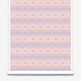 Partially unrolled wallpaper yardage in a gridded paint splatter print in shades of pink, blue, tan and white.