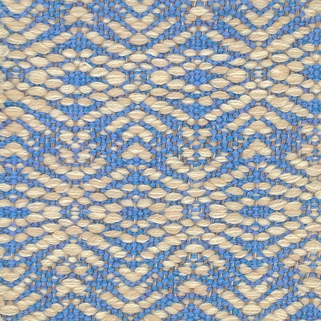 Flatwoven rug with a raised geometric linear design in cream on a bright blue field.