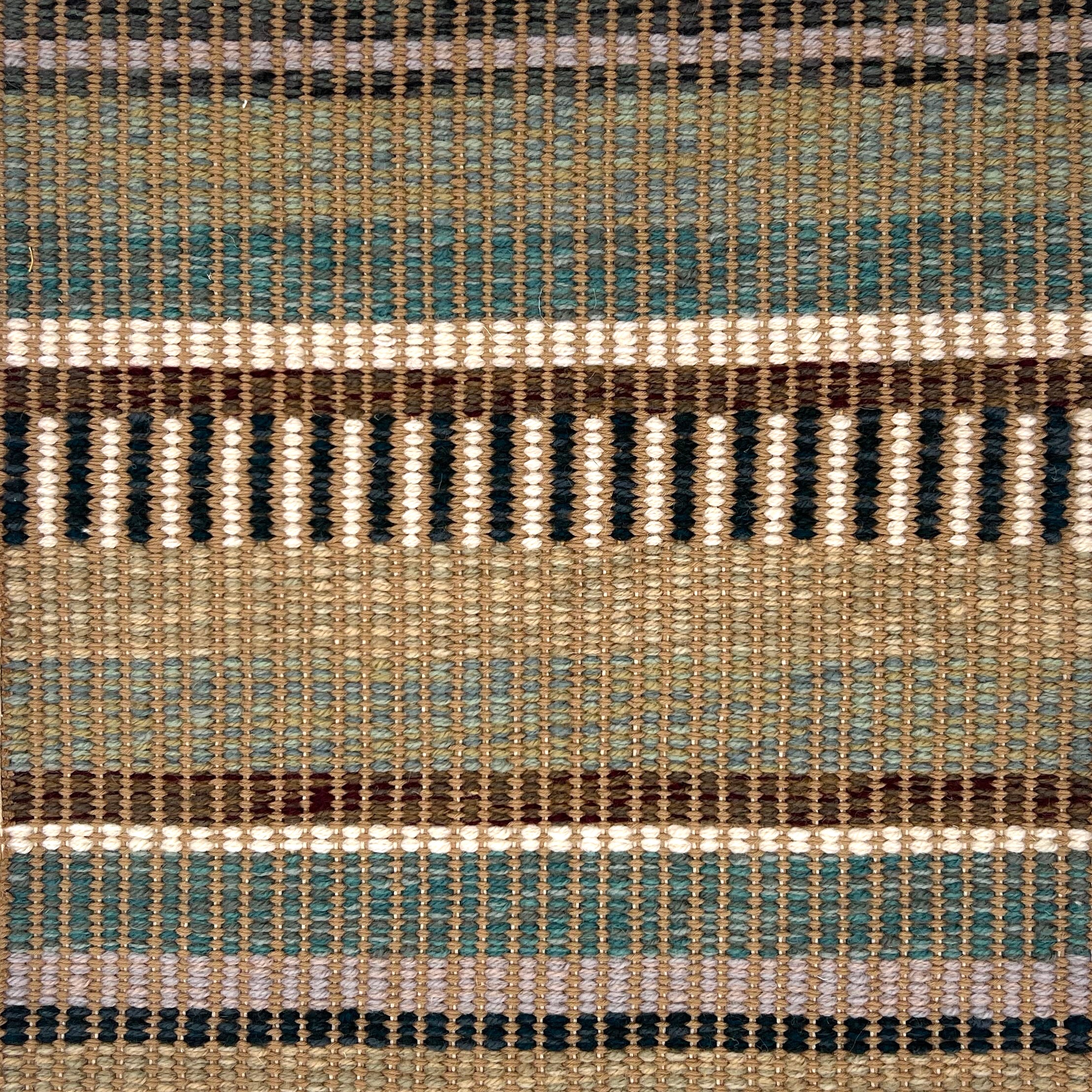 Textural flatweave rug in a varigated stripe design in brown, teal, green and cream.