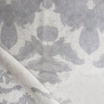 Draped fabric yardage in a watercolor ikat print in shades of gray on a greige field.