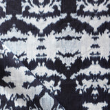 Draped fabric yardage in a watercolor ikat print in shades of blue and navy on a greige field.