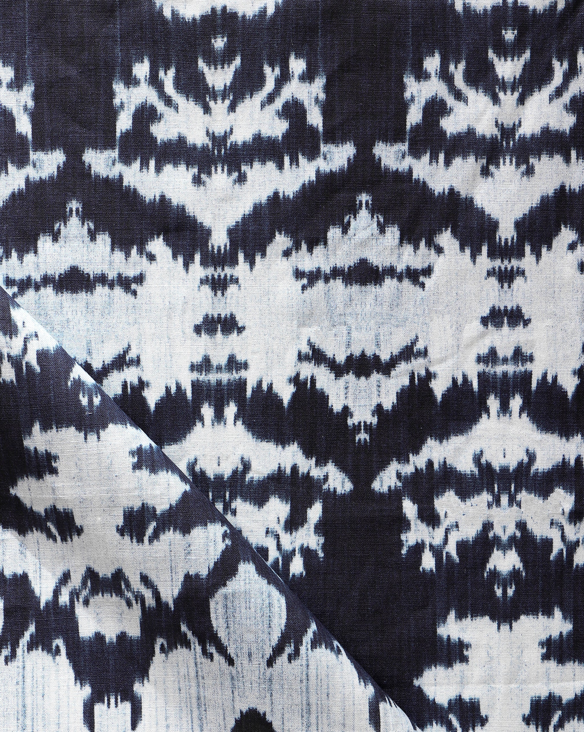 Draped fabric yardage in a watercolor ikat print in shades of blue and navy on a greige field.