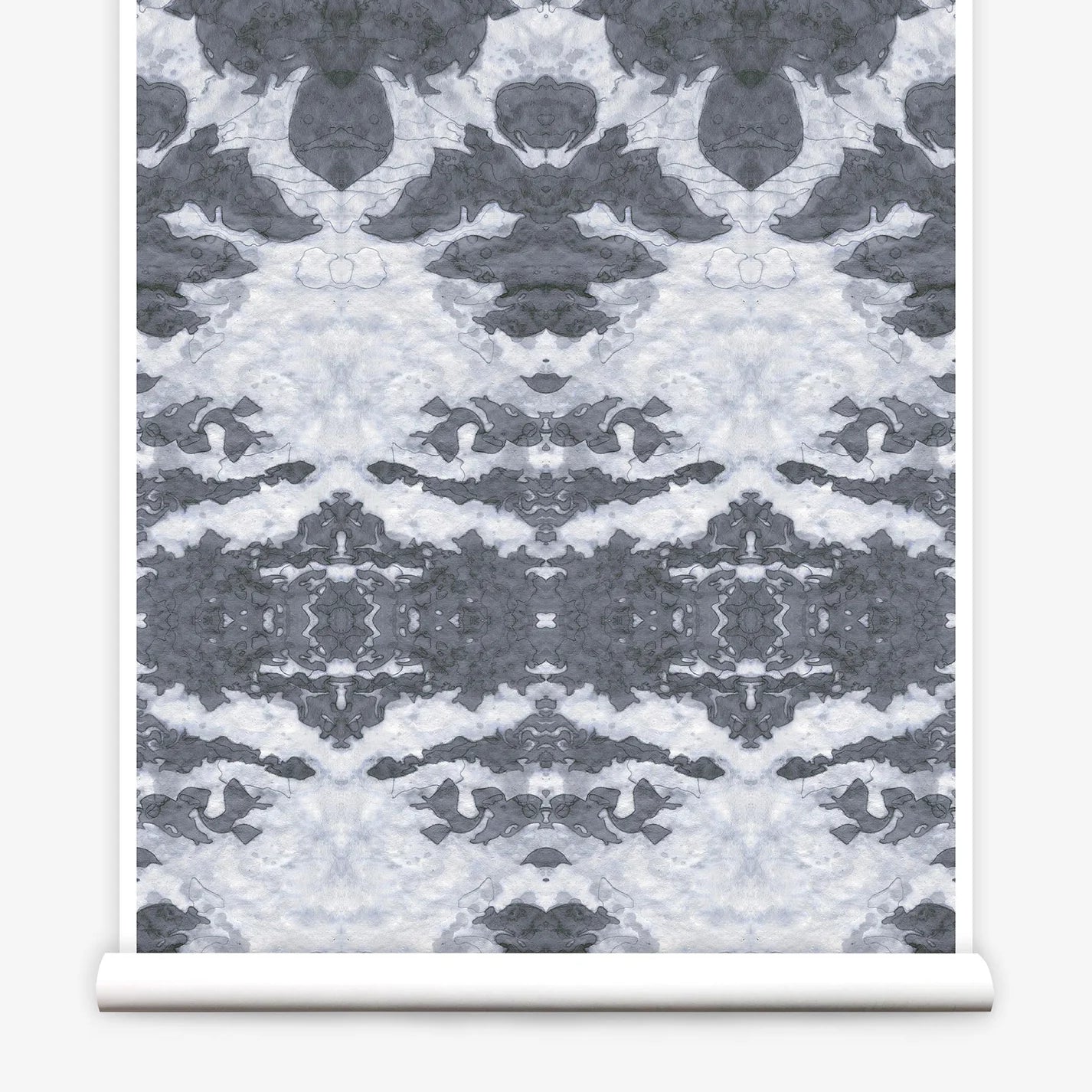 Partially unrolled wallpaper yardage in a painterly ikat print in shades of gray and light blue.