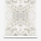 Partially unrolled wallpaper yardage in a watercolor textural print in shades of cream, gray and tan.