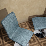 Overhead shot of two upholstered pestal chairs with a blue zebra pattern upholstery on a square patterned rug in brown against wallaper with white dots scattered on a tan field.