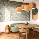 A modernist dining room with a statement wall papered in a painterly palm tree pattern in green, brown and blue-gray.