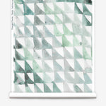 Partially unrolled wallpaper yardage in a painterly check pattern in shades of green and white.