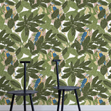 Two minimalist black chairs stand in front of a wall papered in a botanical and parrot print in green, blue and yellow.