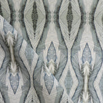 Draped fabric yardage in a watercolor diamond print in shades of gray and navy on a cream field.