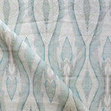 Draped fabric yardage in a watercolor diamond print in shades of gray and blue on a cream field.