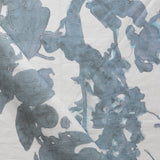 Draped fabric yardage in a watercolor tree print in blue and turquoise on a cream field.