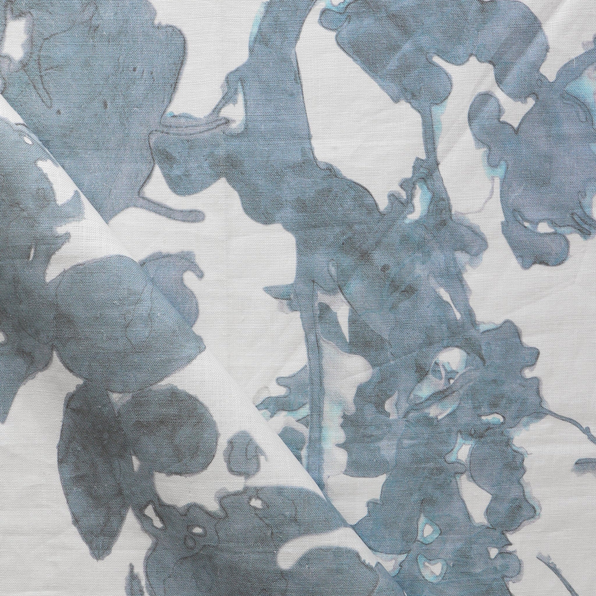 Draped fabric yardage in a watercolor tree print in blue and turquoise on a cream field.