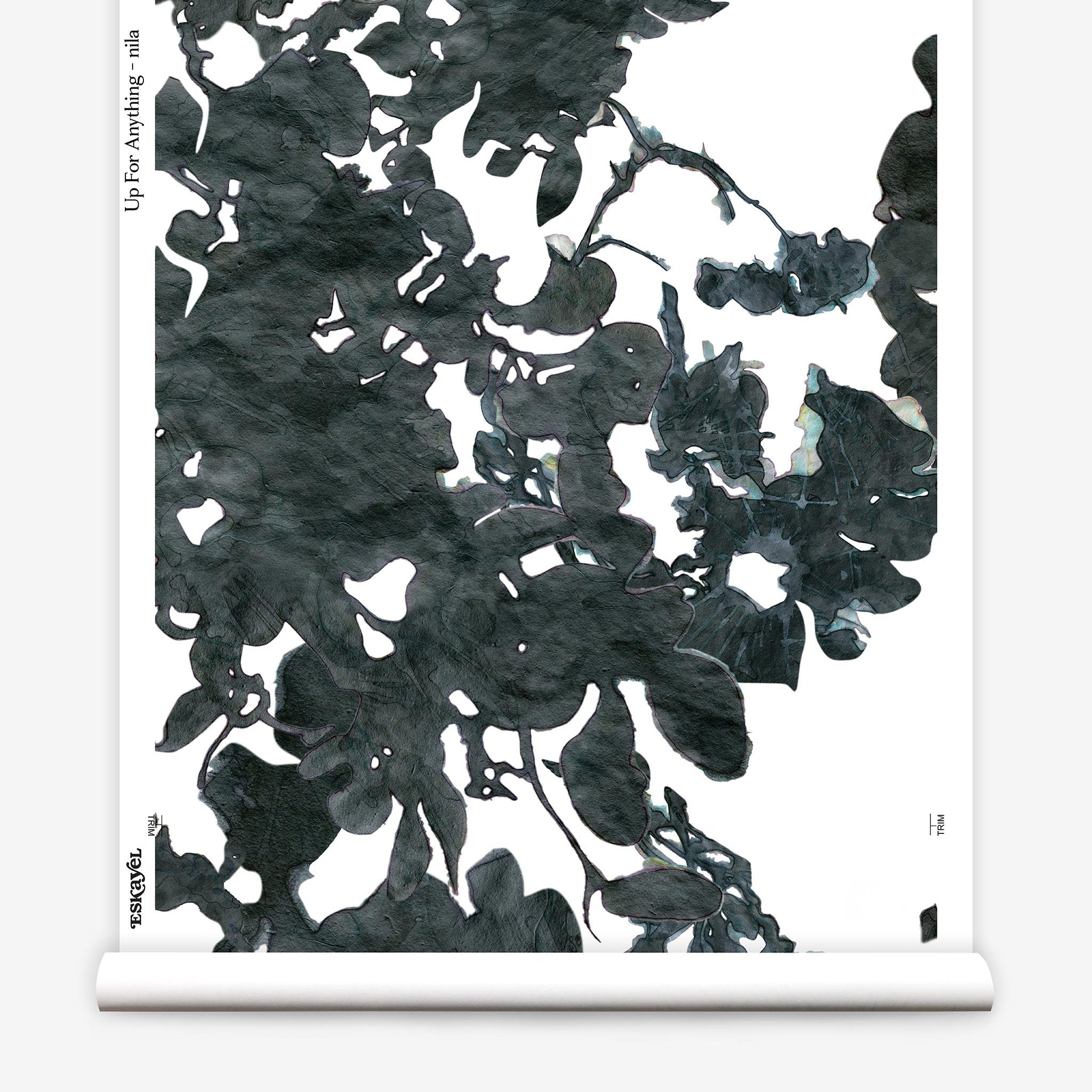 Partially unrolled wallpaper yardage in a watercolor floral print in mottled charcoal and blue on a white field.