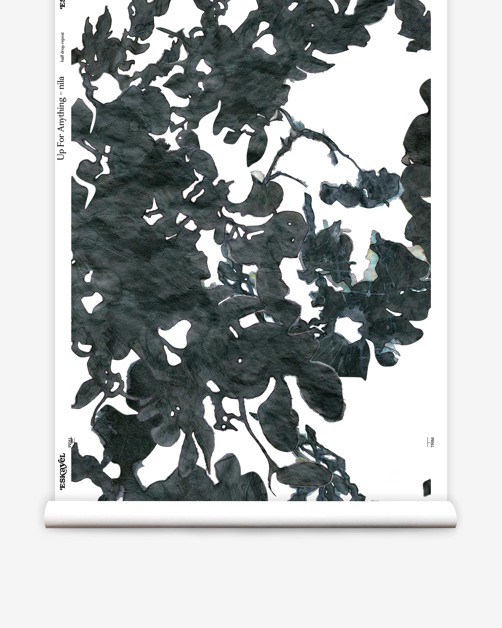 Partially unrolled wallpaper yardage in a watercolor floral print in mottled charcoal and blue on a white field.