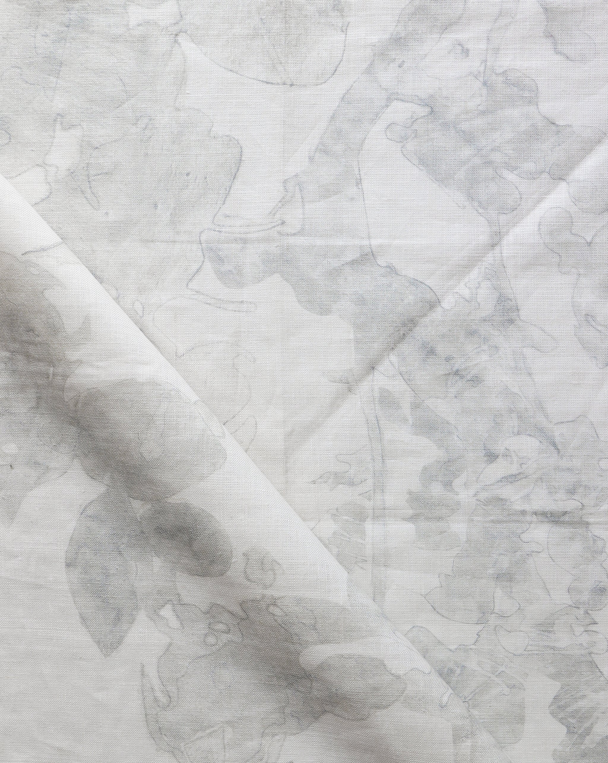 Draped fabric yardage in a watercolor tree print in shades of gray on a cream field.