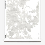 Partially unrolled wallpaper yardage in a watercolor floral print in mottled cream and gray on a white field.