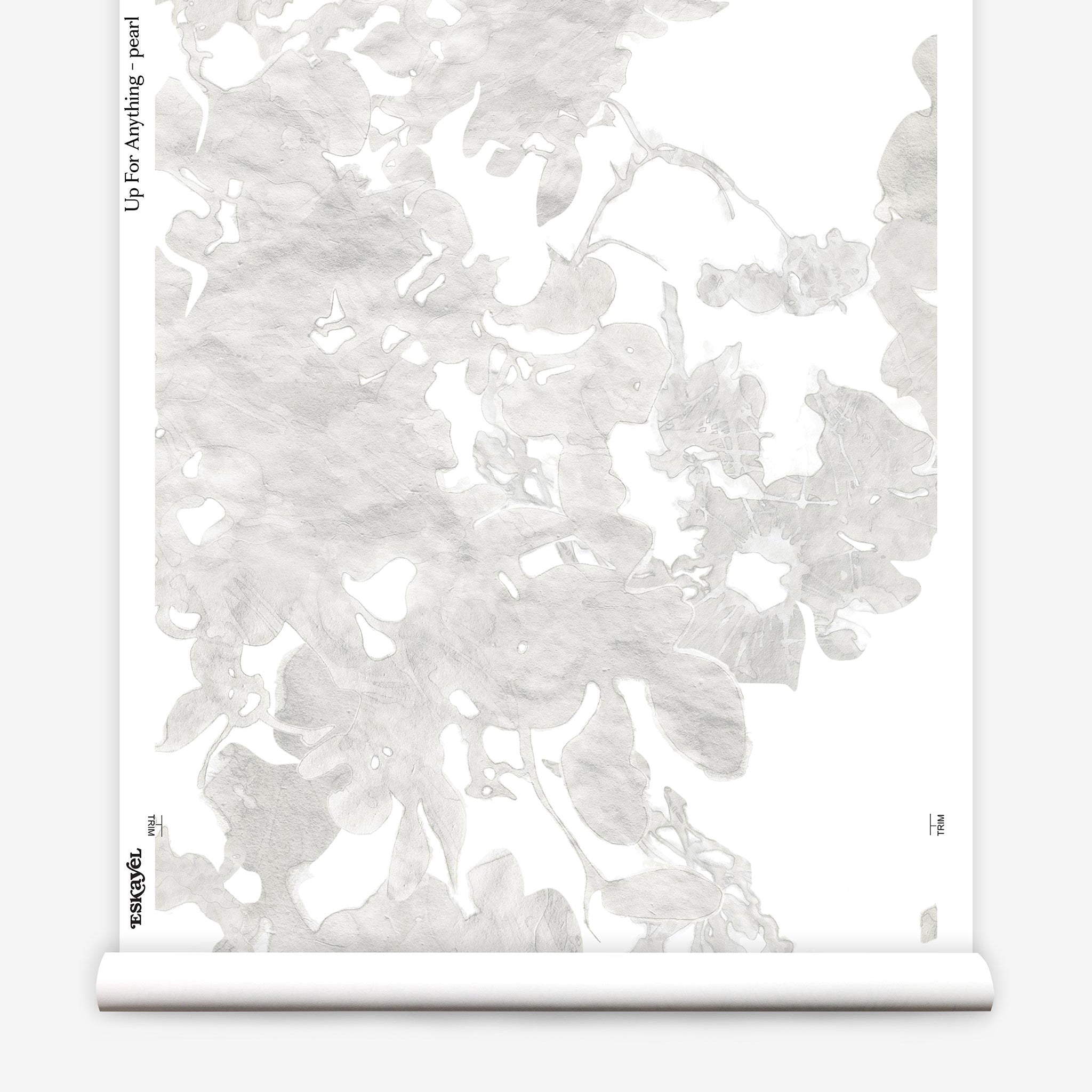 Partially unrolled wallpaper yardage in a watercolor floral print in mottled cream and gray on a white field.