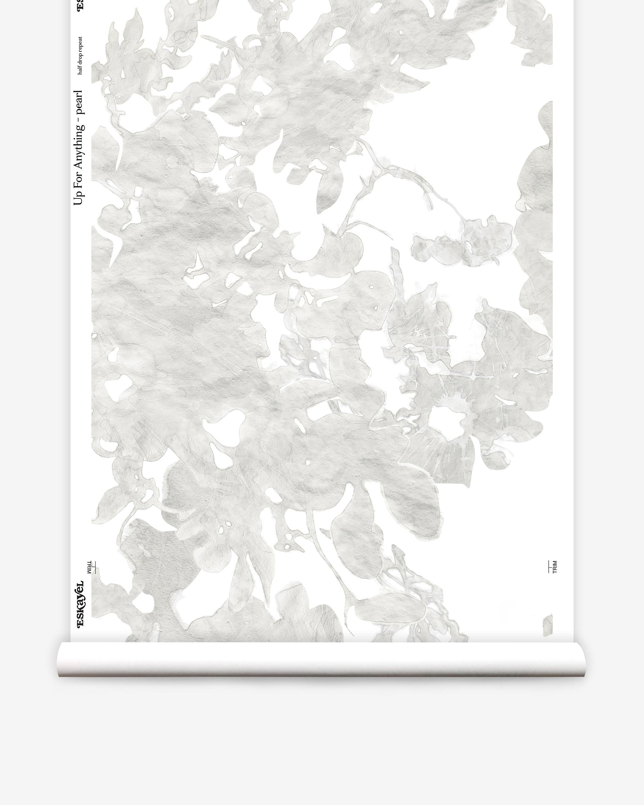 Partially unrolled wallpaper yardage in a watercolor floral print in mottled cream and gray on a white field.
