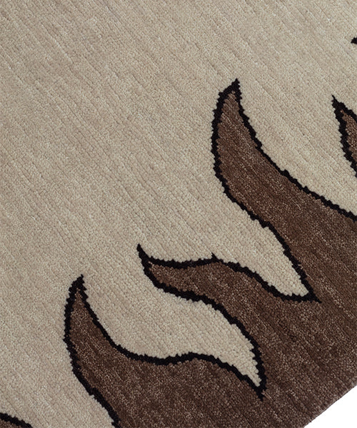 Detail of a handknotted rug with a flame border design in brown on a cream field.