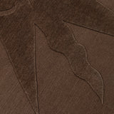 Detail of a handknotted rug with a raised sun motif in tonal brown.
