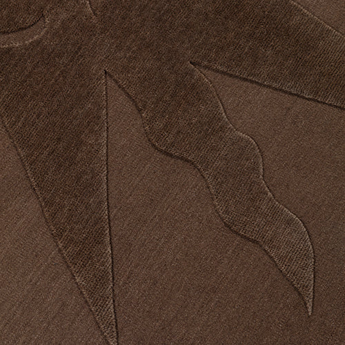 Detail of a handknotted rug with a raised sun motif in tonal brown.
