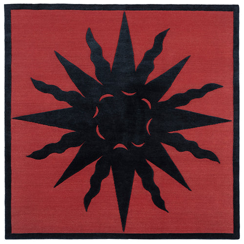 Handknotted rug with a raised sun motif in black on a red field with thin black border.