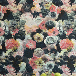 A vase of flowers stands in front of a wall covered in a dense photorealistic floral print in pink and green on a navy field.