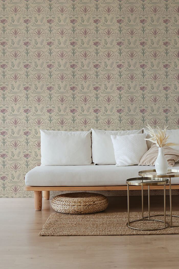 A couch and wooden end table stand in front of a wall papered in an intricate floral lattice print in green, purple and cream.