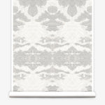 Partially unrolled wallpaper yardage in a painterly ikat print in shades of gray and cream.