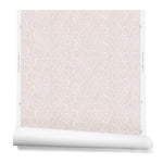 A hanging roll of wallpaper with a large-scale repeating leaf print in white on a light pink watercolor background.