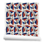 A hanging roll of wallpaper with a repeating pattern of large-scale graphic flowers in red and navy on a cream background.