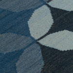 Detail of Alhambra Rug featuring a pattern of linked circles that create a star like lattice in a range of blue shades, from pale blue to chambray, indigo, to dark navy