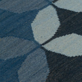 Detail of Alhambra Rug featuring a pattern of linked circles that create a star like lattice in a range of blue shades, from pale blue to chambray, indigo, to dark navy