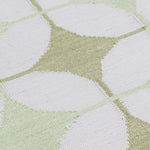 Detail of Alhambra Rug in Olive featuring pattern of linked circles that create a star like lattice in a soft olive and lime green on an ivory field. 