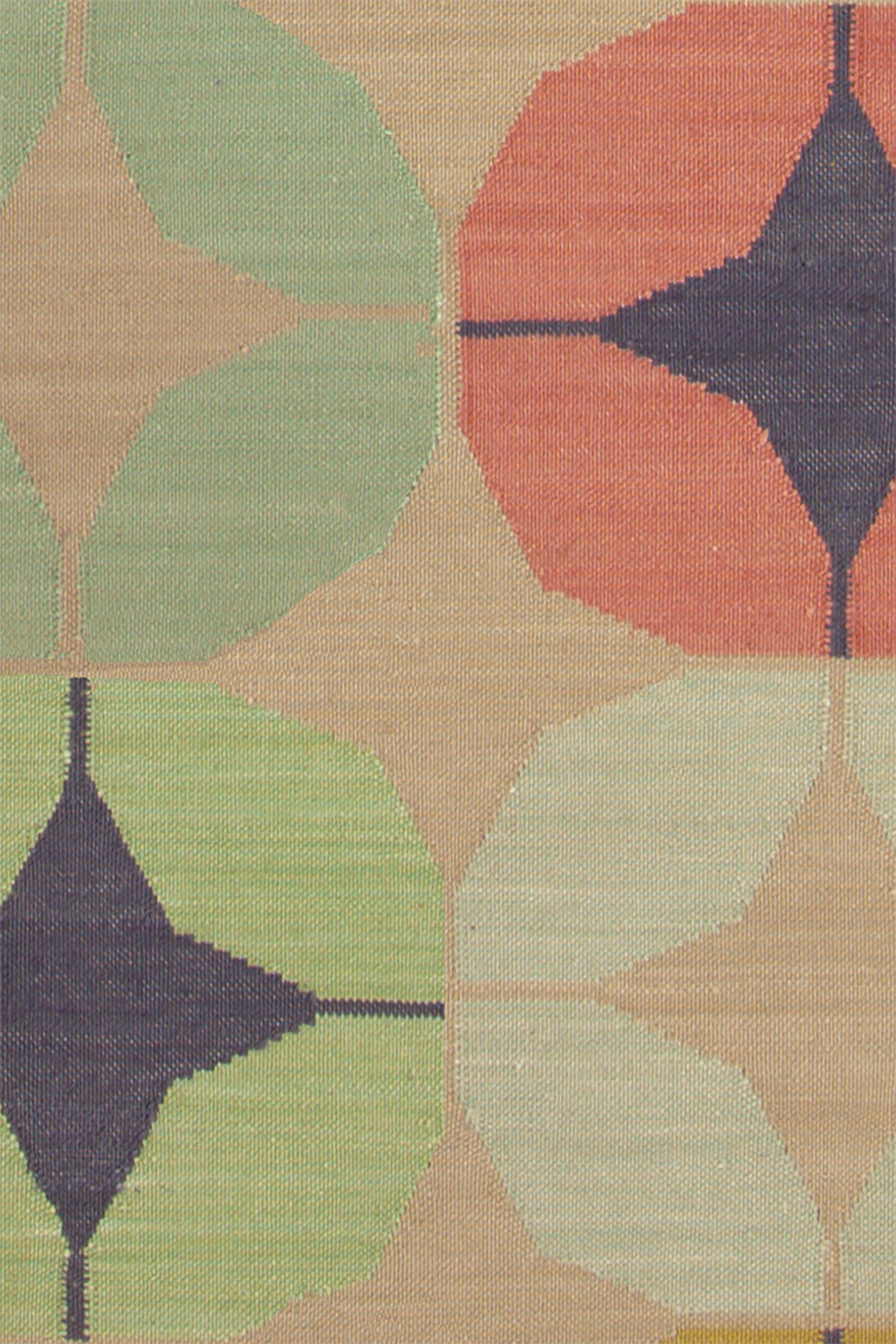 Detail of Alhambra Rug in Venetia featuring pattern of linked circles that create a star like lattice in a range of coral, mustard tyellow, seafoam green, pale green and royal purple accents on a tan field. 