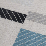 Detail of the Amelia Rug in Camara featuring a minimalist broken stripe pattern, overlayed with thin white diagonal lines. The broken stripes are a mix of black, pale blue and turquoise with accents of red and bright yellow, all on a soft grey field