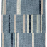 Full size Amelia Rug in Lapiz featuring a minimalist broken stripe pattern, overlayed with thin light blue diagonal lines. The broken stripes are a mix of navy blue, pale blue. white and turquoise with black accents, all on denim blue field.