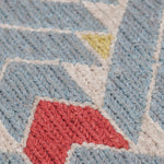 Detail of the Arrow Rug in Powder Blue-Coral features a dense pattern of nesting arrow shapes in soft blue with accents of coral and yellow on an ivory field. 
