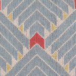 Detail of the Arrow Rug in Powder Blue-Coral features a dense pattern of nesting arrow shapes in soft blue with accents of coral and yellow on an ivory field. 