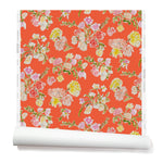 Partially unrolled wallpaper with a pattern of large-scale line-drawn flowers in gray ink with red, pink and yellow watercolors, on a red background.