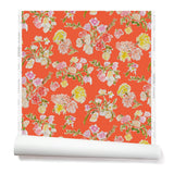 Partially unrolled wallpaper with a pattern of large-scale line-drawn flowers in gray ink with red, pink and yellow watercolors, on a red background.