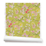 Partially unrolled wallpaper with a pattern of large-scale line-drawn flowers in gray ink with red, pink and yellow watercolors, on a light green background.