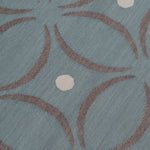 Detail of the Boe rug in Argento, featuring a pattern of curved segments in grey with white circles on a blue field. 