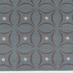 Detail of the Boe rug in Argento, featuring a pattern of curved segments in grey with white circles on a blue field. 