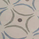 Detail of the Boe rug in Genoa, featuring a pattern of curved segments in light blue and sage green with taupe circles on an ivory field. 