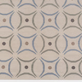 Detail of the Boe rug in Genoa, featuring a pattern of curved segments in light blue and sage green with taupe circles on an ivory field. 