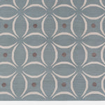 Detail of the Boe rug in Argento, featuring a pattern of white curved segments with taupe circles on a blue field. 