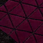 Detail of the Bucky Rug in berry, features a wide black border with a wine colored lattice field with a metallic sheen. 